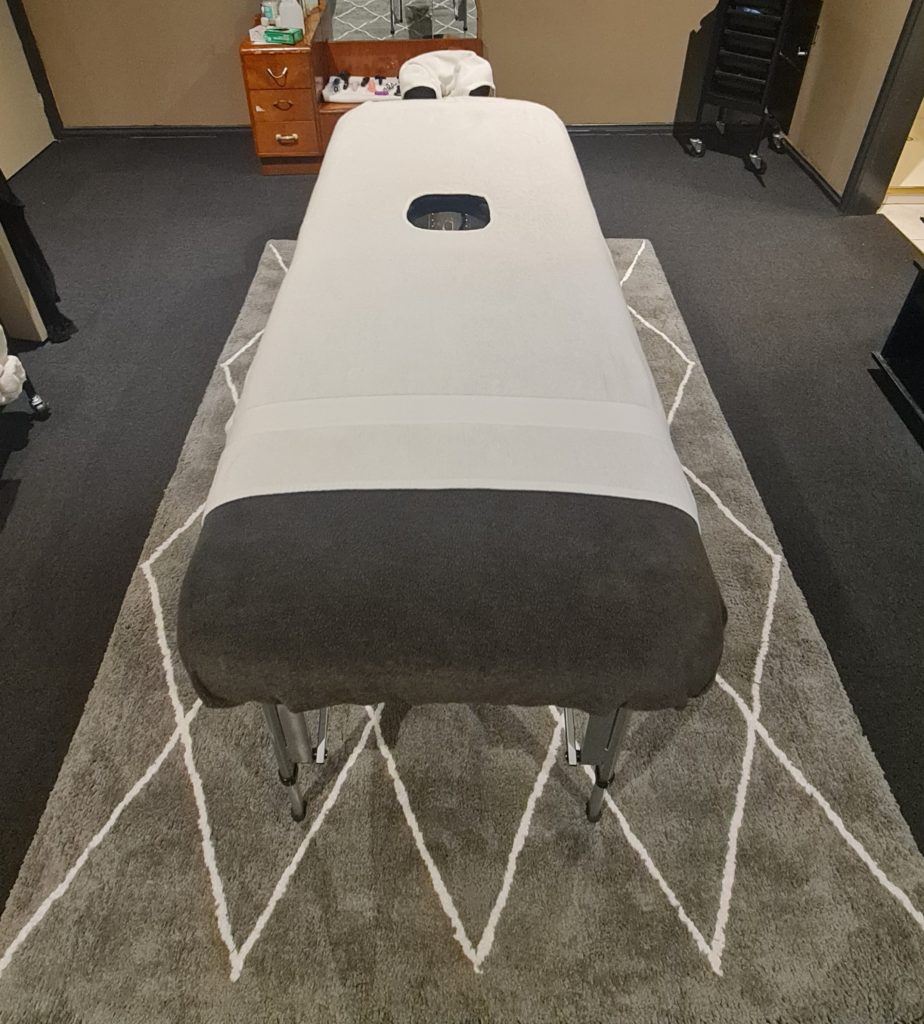 A milking table on a grey carpet with custom white towels sewn with ana additional hole.